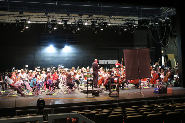 students listening to director on stage